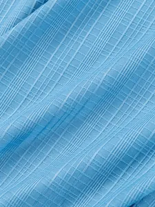 Primer plano de tela azul claro con textura flameada para camisas de verano de hombre.