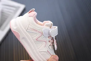Detailopname van roze-witte peutersneakers met klittenbandsluiting en lederen afwerking.
