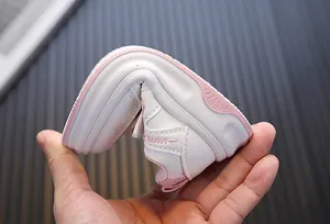 Detailopname van de flexibele en zachte zool van wit-roze leren kinderschoenen.