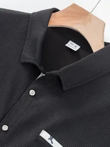Nahaufnahme von schwarzem Waffelstrickstoff und Größenetikett bei Herren-Polohemd
