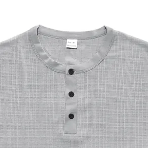 Détail du col d'un t-shirt Henley gris texturé avec trois boutons noirs.