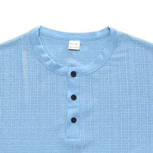Détail macro d'un t-shirt Henley bleu clair pour homme en tissu flammé texturé spécial.
