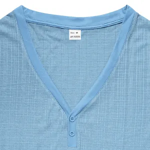 Close-up detail of light blue textured Henley shirt with V-neckline and buttons.