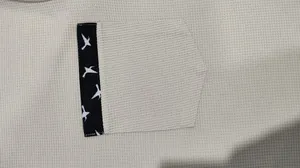 Detailansicht der Waffelstrick-Textur und Vogelmuster-Tasche am Herren-Freizeitset.