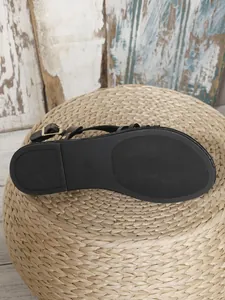Primer plano de la suela antideslizante de sandalias planas negras con marca de talla 37