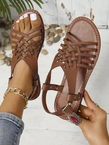 Detalle de sandalias marrones de estilo vintage con tiras cruzadas y cierre de hebilla.