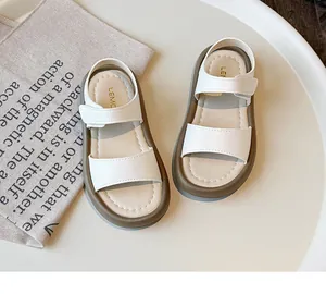 Detail view of stylish white children's summer sandals with soft soles and velcro.