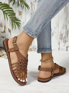 Primer plano de sandalias planas marrones retro con tiras y hebilla ajustable para mujer