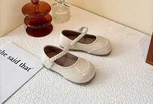 Detailed view of cream girls' Mary Jane shoes with elegant braided strap detail