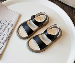 Close-up of girls' minimalist black leather sandals with soft soles.