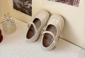 Close-up detail view of cream Mary Jane shoes for girls featuring an elegant braided strap