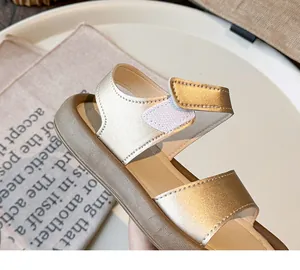 Detail of gold girl's sandal featuring adjustable velcro strap and soft sole
