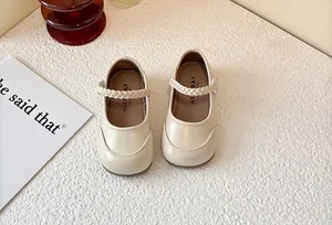 Close-up detail of cream Mary Jane shoes for girls featuring a braided strap and soft sole.