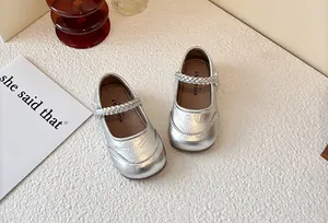 Detailed top-down view of silver metallic Mary Jane shoes for girls on textured surface
