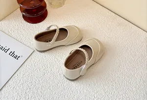 Detailed top-down view of cream-colored kids Mary Jane shoes with braided strap