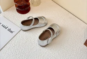 Close-up of silver girls' Mary Jane shoes with metallic finish and braided strap