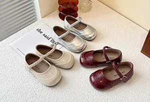 Detail of girls' Mary Jane shoes in silver, beige and dark red with braided straps.