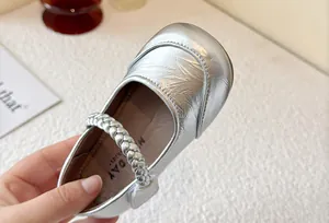 Detailed view of silver girl's princess shoe with braided strap and metallic texture