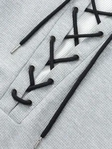 Close-up detail of a grey waffle knit men's t-shirt featuring a black lace-up design with grommets