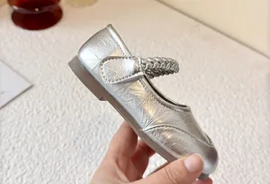 Detailed view of silver metallic children's Mary Jane shoe with a braided strap design