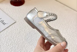 Detailed view of silver metallic girls Mary Jane shoe with braided velcro strap