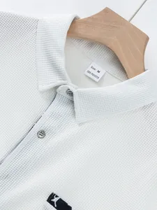Detail of a men's white waffle knit polo shirt showing collar, buttons, and neckline size label.