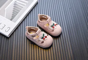 Close-up view of pink toddler sandals featuring cute embroidered cherries and lace trim