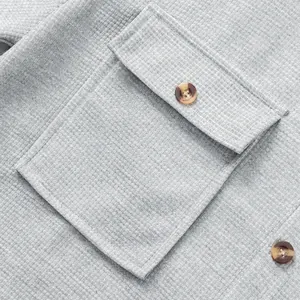 Close-up detail of grey waffle knit fabric with pocket and button on men's shirt