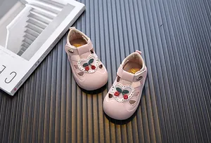 Detail of pink toddler sandals with cute cherry embroidery and heart lace on a dark background.