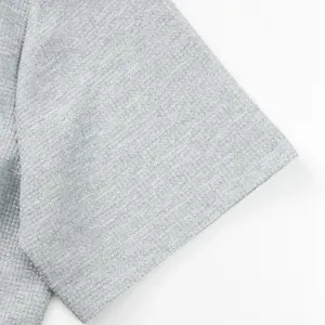 Detailed macro view of grey waffle knit fabric texture on a short-sleeve shirt