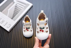 Close-up of white toddler girl sandals with cherry embroidery and hollowed-out design.
