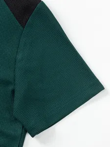 Close-up of dark green waffle knit fabric and stitching on a men's short sleeve T-shirt.
