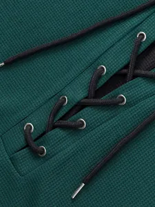 Macro detail of waffle knit fabric and black lace-up drawstring on a teal men's t-shirt