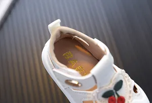 Detail view of white baby girl walking sandals featuring soft collar and cherry embroidery