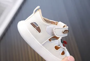 Close-up detail of white toddler sandal with red cherry and Velcro strap