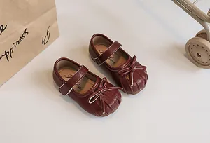 Detailed macro view of burgundy girls' pleated Mary Jane shoes with bow decoration