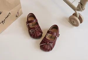 Close-up of burgundy girls' pleated Mary Jane shoes with bow detail and soft sole