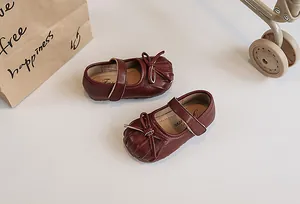 Detailed view of burgundy girl's leather shoes featuring bow and pleated toe design.