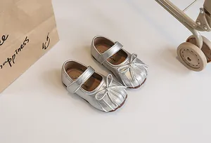 Detail view of silver metallic girl's Mary Jane shoes with a decorative bow and pleated toe