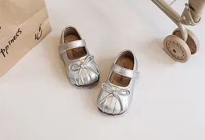 Close-up detail of silver girl's princess shoes with pleated toe and bow decoration
