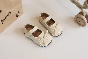 Detailed shot of cream-colored pleated Mary Jane shoes for girls with elegant bow.