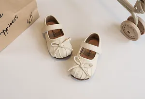 Detailed view of beige girls' Mary Jane shoes featuring a bow and pleated toe design.