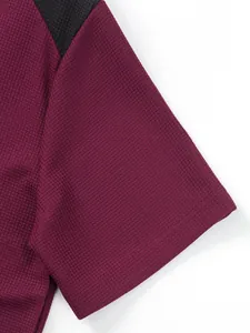 Close-up view of the waffle knit fabric and stitching on a burgundy men's t-shirt sleeve