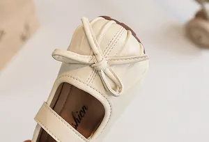 Close-up of pleated toe detail and bow on girl's cream leather princess shoe