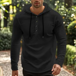 Detailansicht eines schwarzen langärmeligen Herren-Henley-Kapuzenpullovers im Freien.