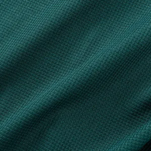 Close-up detail of dark teal waffle knit fabric showing premium texture and weave pattern.