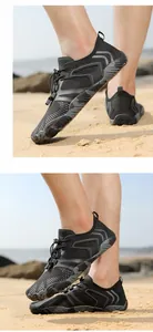 Detailaufnahme schwarzer, schnelltrocknender Watelschuhe an einem sonnigen Sandstrand