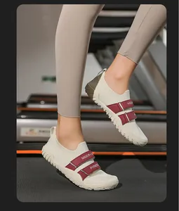 Vue détaillée de chaussures d'haltérophilie crème avec sangles rouges sur tapis.