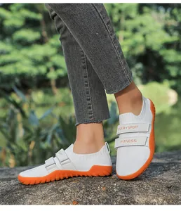 Vue détaillée de chaussures de fitness blanches avec semelles orange et bandes velcro
