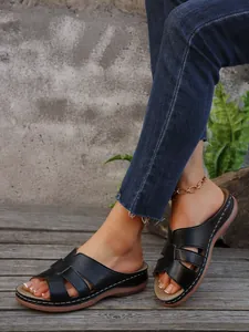 Detalle de cómodas sandalias de cuña negras para mujer en una terraza de madera